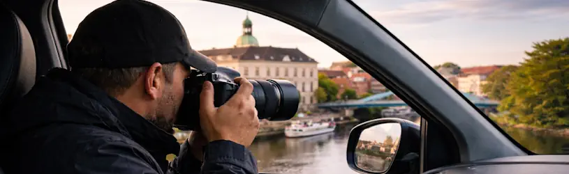 Privatdetektiv in Oldenburg sitzt in einem Fahrzeug und fotografiert diskret aus dem Auto heraus während einer Observation.