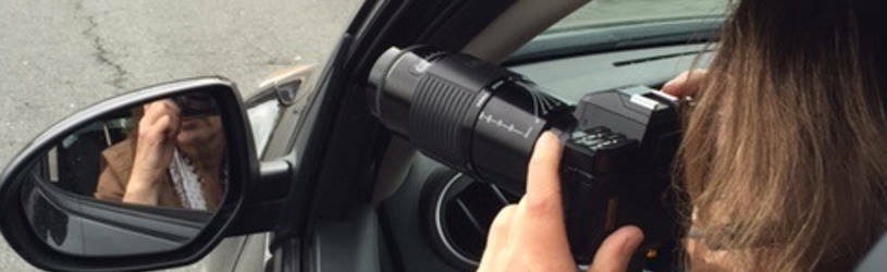 Privatdetektivin sitz fotografierend im Auto und observiert.